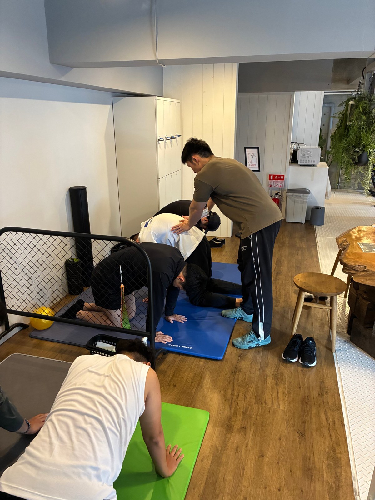 マットの上で体をほぐす参加者と、背中に手を当てて確認するトレーナー